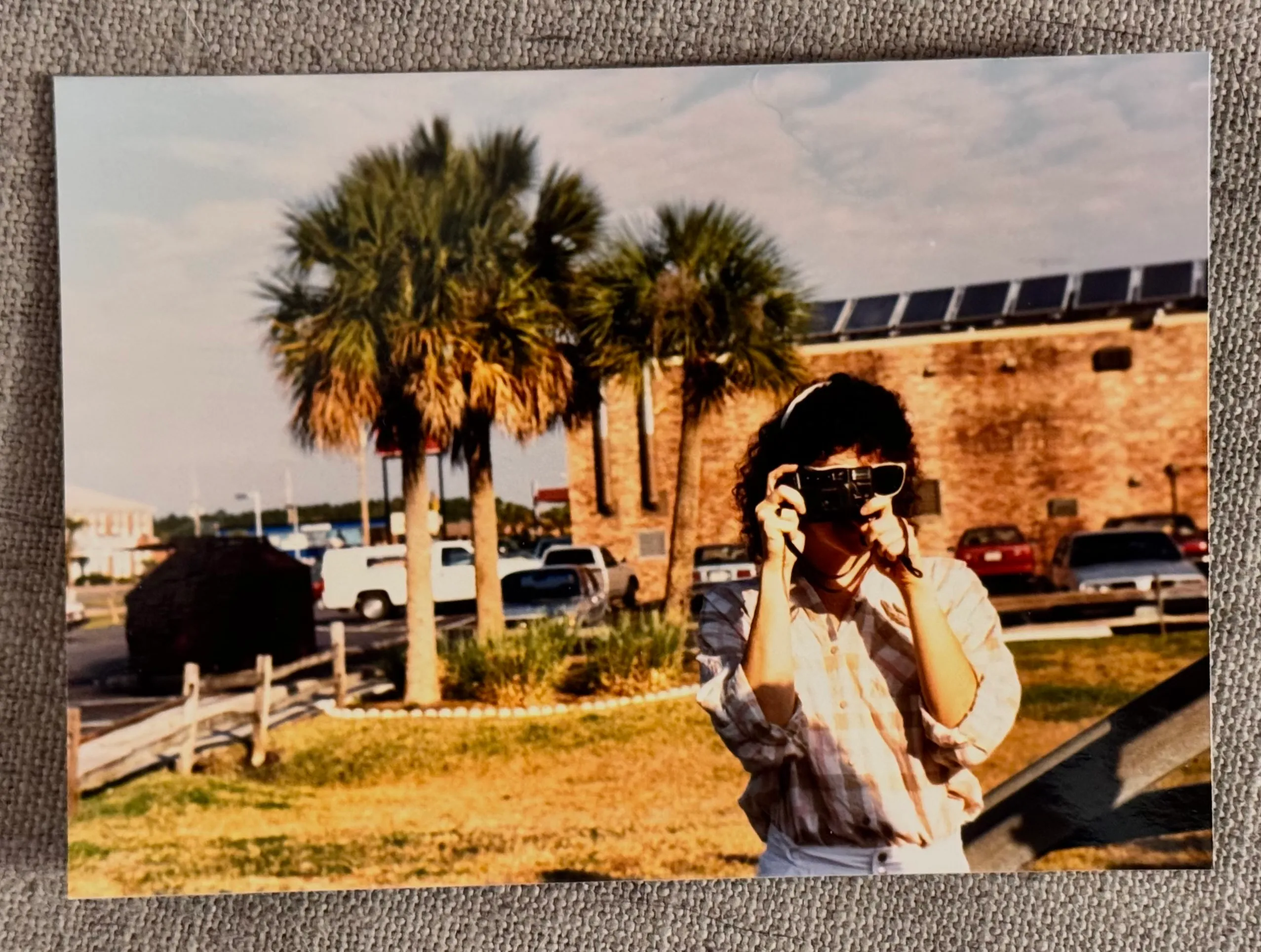 Val around age 20 pointing a camera at the photographer, the camera is obscuring her face